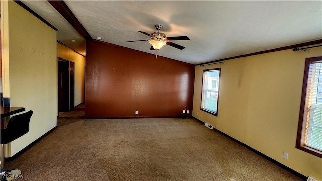 carpeted empty room featuring a healthy amount of sunlight, crown molding, and vaulted ceiling