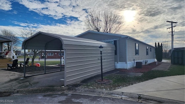 view of side of home with a storage unit, central AC unit, and a carport