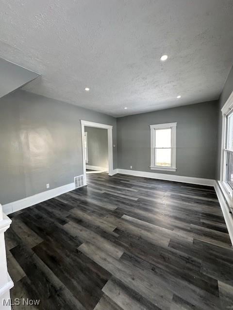 empty room with a textured ceiling and dark wood-type flooring