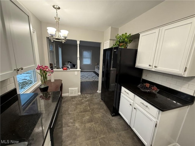 kitchen featuring backsplash, white cabinetry, hanging light fixtures, and black refrigerator with ice dispenser