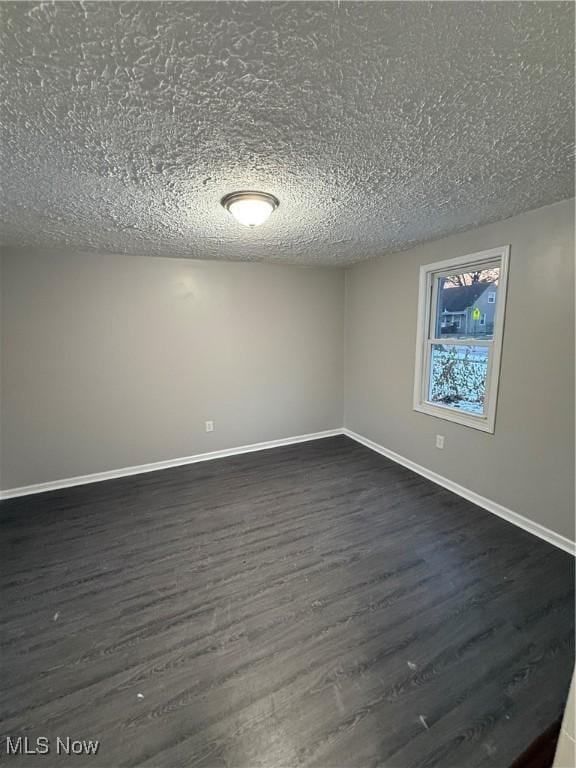 empty room featuring a textured ceiling and dark wood-type flooring