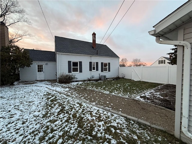 snow covered rear of property featuring central air condition unit