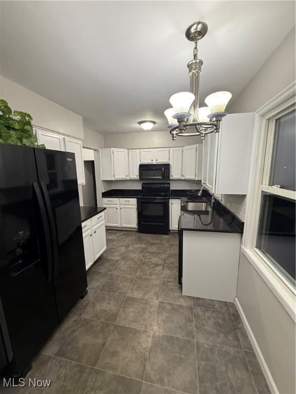 kitchen with pendant lighting, black appliances, white cabinets, sink, and a notable chandelier