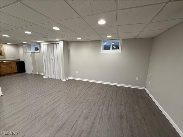 basement with hardwood / wood-style floors and a paneled ceiling