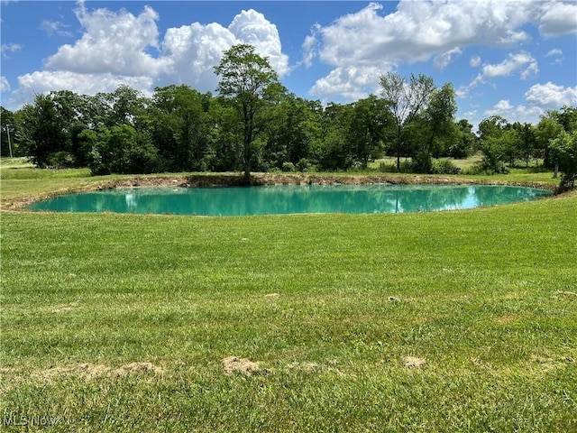 view of pool with a water view and a lawn