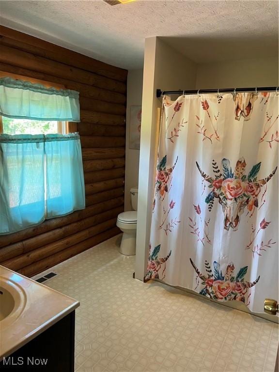 bathroom featuring a textured ceiling, vanity, and rustic walls