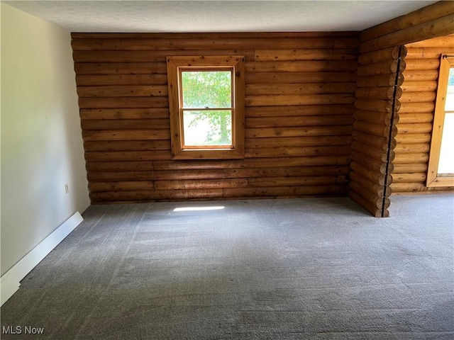 unfurnished room featuring log walls and dark carpet