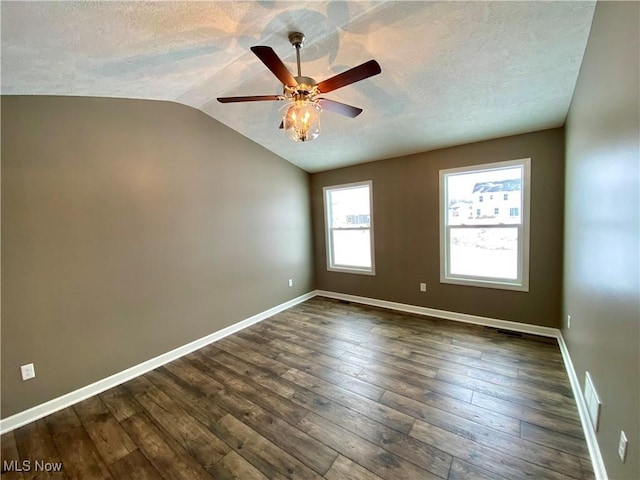 empty room featuring a textured ceiling, ceiling fan, dark wood-type flooring, and vaulted ceiling