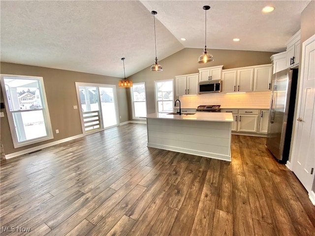 kitchen featuring pendant lighting, vaulted ceiling, dark hardwood / wood-style floors, white cabinetry, and stainless steel appliances