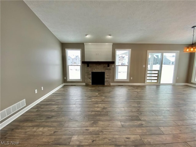 unfurnished living room featuring a textured ceiling, an inviting chandelier, a fireplace, and dark wood-type flooring