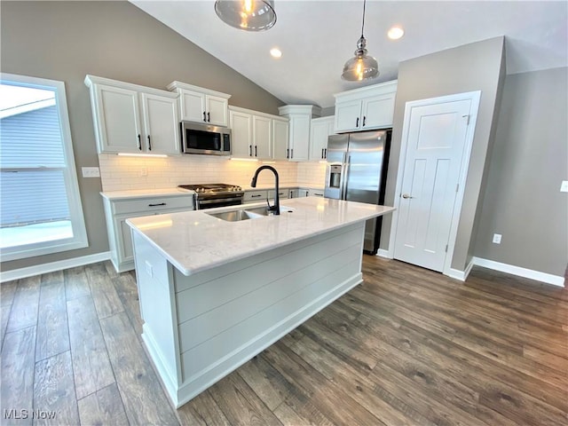 kitchen with appliances with stainless steel finishes, vaulted ceiling, sink, decorative light fixtures, and white cabinets