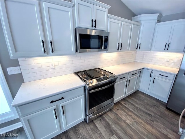 kitchen featuring decorative backsplash, stainless steel appliances, white cabinets, dark hardwood / wood-style floors, and lofted ceiling