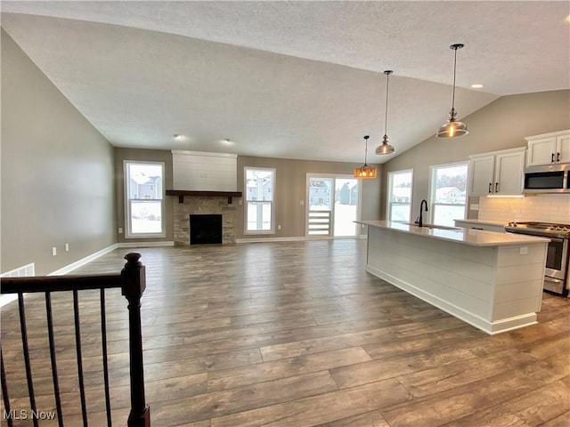 kitchen featuring a kitchen island with sink, dark wood-type flooring, vaulted ceiling, white cabinetry, and stainless steel appliances