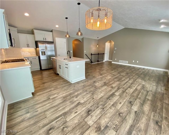 kitchen featuring light hardwood / wood-style floors, an island with sink, hanging light fixtures, and appliances with stainless steel finishes