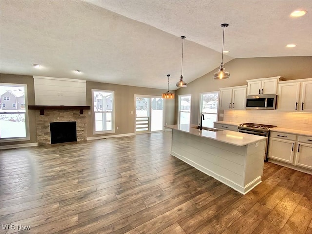 kitchen featuring appliances with stainless steel finishes, vaulted ceiling, dark wood-type flooring, white cabinets, and plenty of natural light