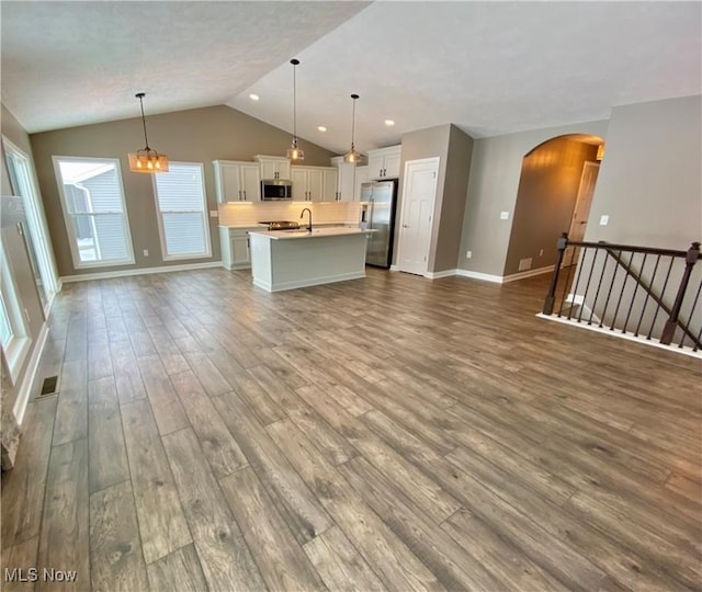 kitchen with pendant lighting, stainless steel appliances, white cabinetry, and hardwood / wood-style floors