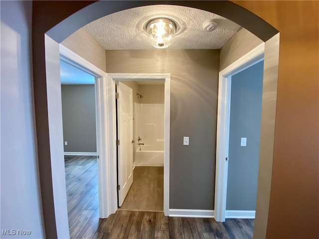 hall featuring a textured ceiling and dark wood-type flooring