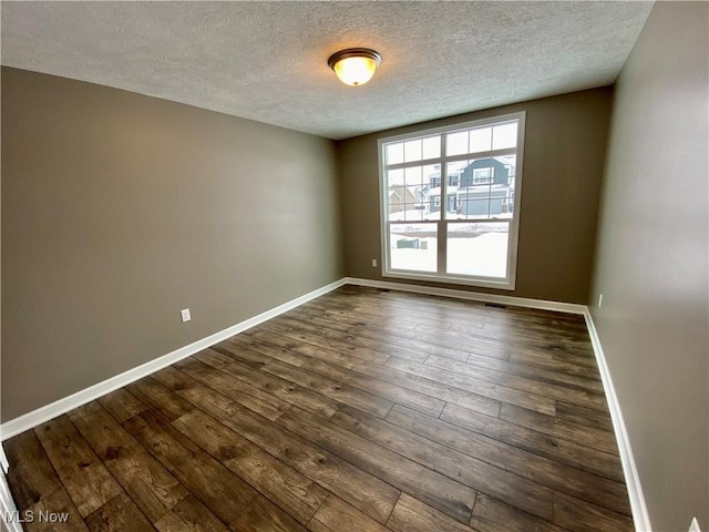 spare room with dark hardwood / wood-style flooring and a textured ceiling