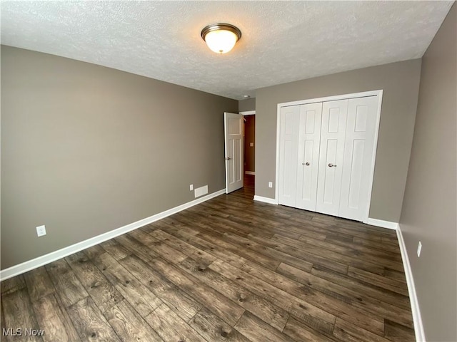 unfurnished bedroom featuring a closet, dark wood-type flooring, and a textured ceiling