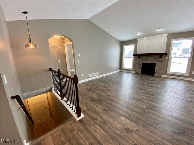 unfurnished living room featuring a wealth of natural light, dark wood-type flooring, and lofted ceiling