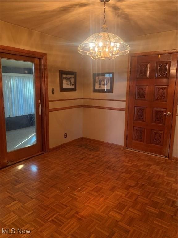 unfurnished dining area featuring parquet flooring and a notable chandelier