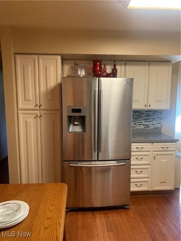 kitchen with white cabinetry, tasteful backsplash, stainless steel fridge with ice dispenser, dark stone countertops, and light hardwood / wood-style floors