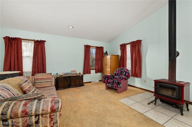 carpeted living room featuring a wood stove and lofted ceiling