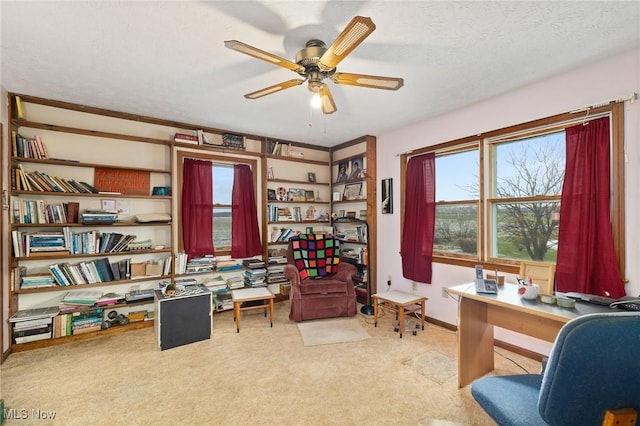 carpeted home office with ceiling fan and a textured ceiling