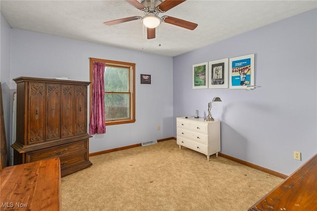 carpeted bedroom with ceiling fan and a textured ceiling