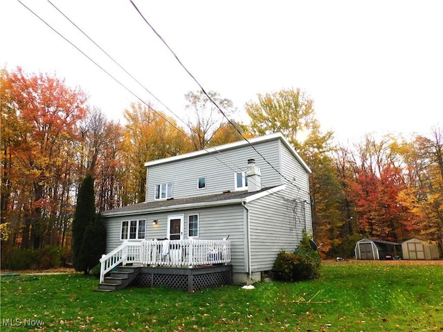 rear view of property featuring a lawn, a storage shed, and a deck