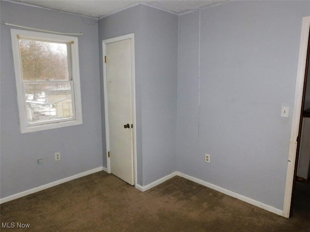 spare room featuring dark colored carpet