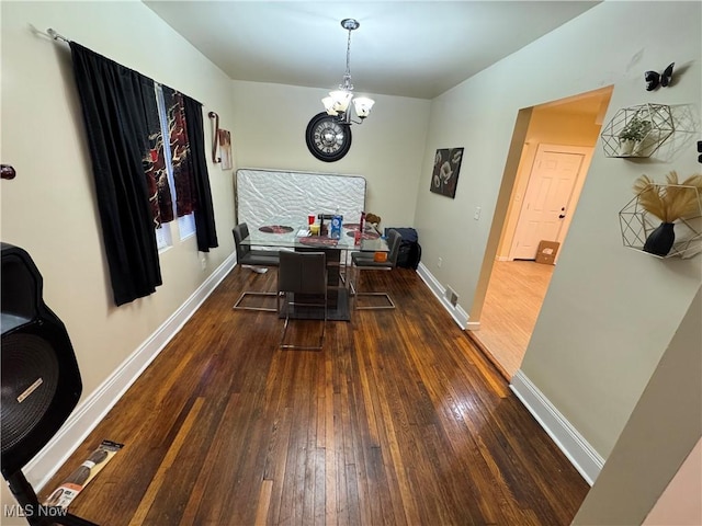 dining area featuring dark wood-type flooring and a notable chandelier