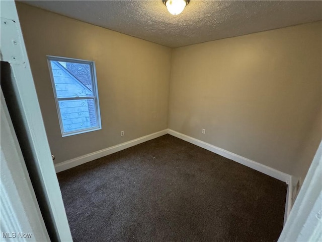 unfurnished room featuring dark carpet and a textured ceiling