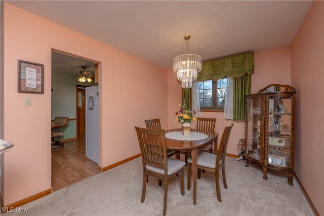 carpeted dining room with ceiling fan with notable chandelier