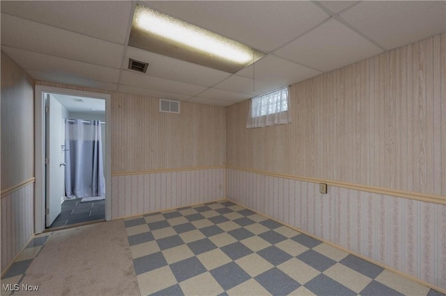 basement featuring a paneled ceiling and dark colored carpet