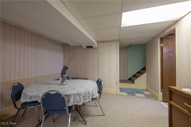 dining room with a paneled ceiling and light colored carpet