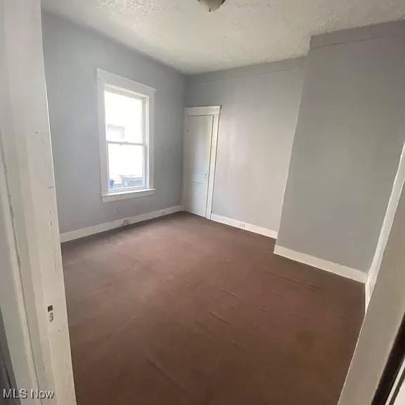 spare room featuring a textured ceiling and dark colored carpet