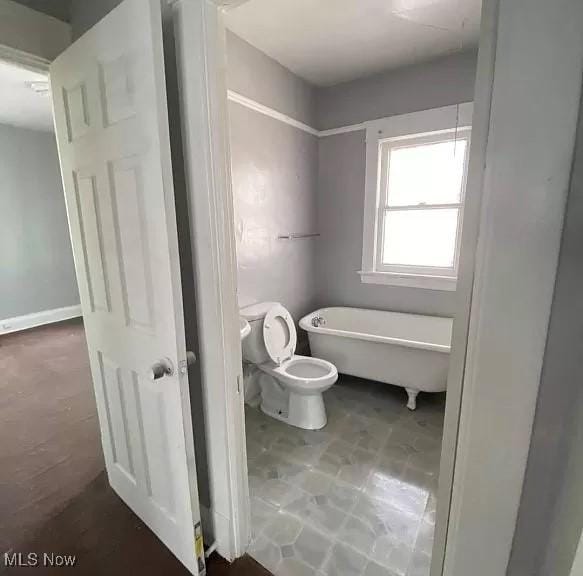 bathroom featuring tile patterned flooring, a bath, and toilet