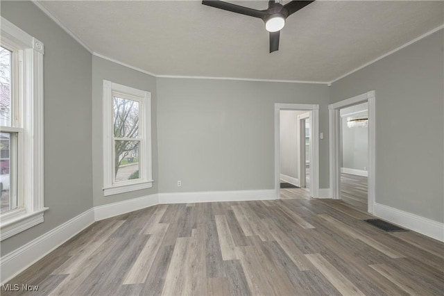 unfurnished room featuring ceiling fan, light hardwood / wood-style flooring, a healthy amount of sunlight, and ornamental molding