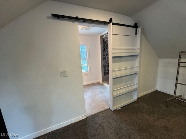 additional living space featuring vaulted ceiling, carpet, and a barn door