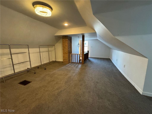 bonus room with dark carpet and vaulted ceiling