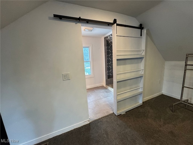 additional living space featuring carpet flooring, a barn door, and vaulted ceiling