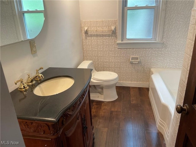 bathroom featuring toilet, a bathtub, wood-type flooring, and vanity