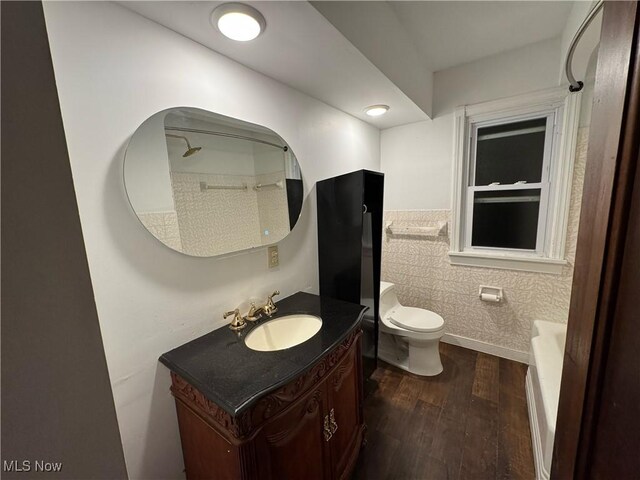 bathroom with toilet, tile walls, wood-type flooring, and vanity