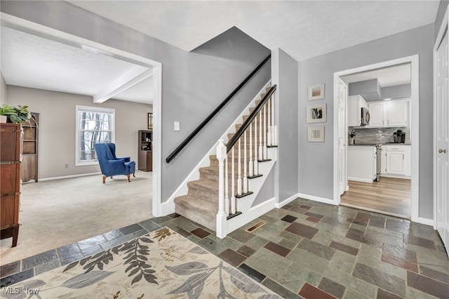 entryway featuring beam ceiling, a textured ceiling, and dark carpet