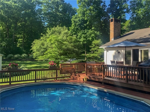 view of swimming pool featuring a lawn and a deck