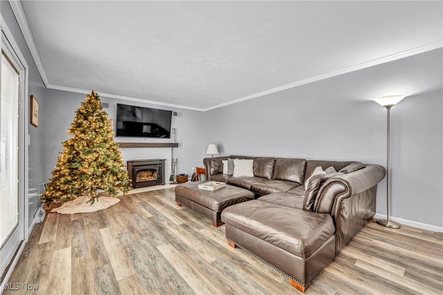 living room featuring light wood-type flooring, a brick fireplace, and ornamental molding