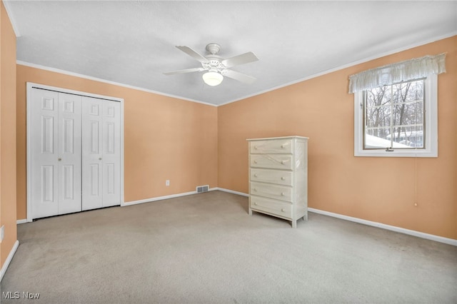 unfurnished bedroom with ceiling fan, crown molding, light carpet, and a closet