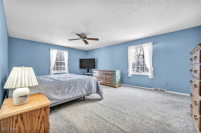 carpeted bedroom with ceiling fan and a textured ceiling