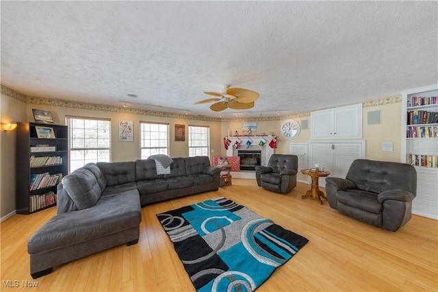 living room featuring wood-type flooring, a textured ceiling, and ceiling fan